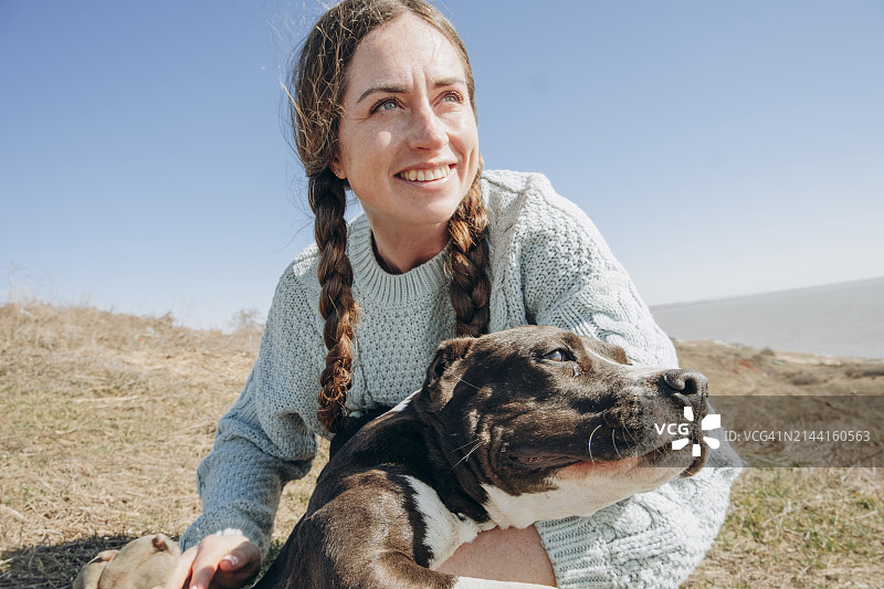 阳光明媚的日子里，快乐的女人和狗在山丘上图片素材