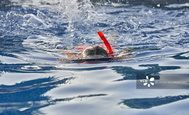 戴游泳镜的少女在泳池水面练习游泳图片素材