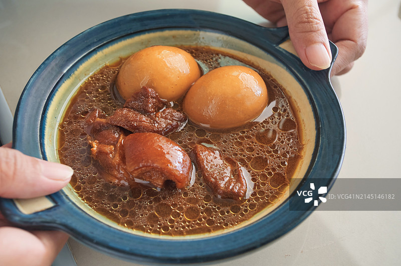 手捧一碗红烧鸡蛋和猪肉图片素材