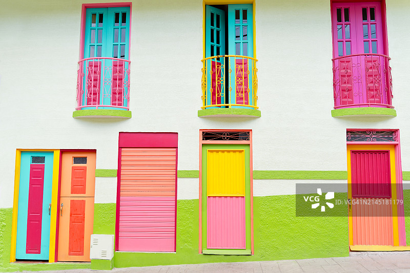 哥伦比亚马尼萨莱斯老城区色彩鲜艳的殖民时期房屋，带有粉红色木门和蓝色凸窗图片素材