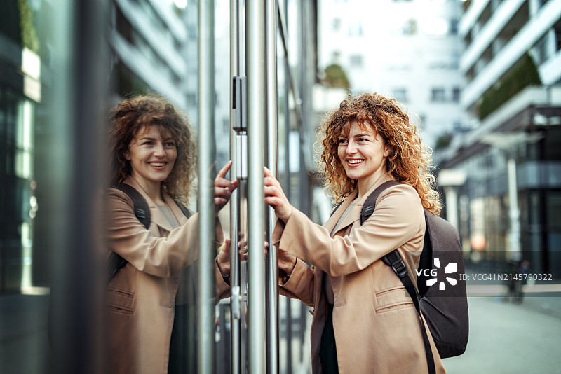 在公司门前输入PIN码的漂亮年轻女商人侧视图图片素材