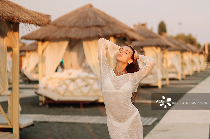 穿着时尚海滩装的年轻漂亮女子在海滩上摆姿势看向镜头图片素材