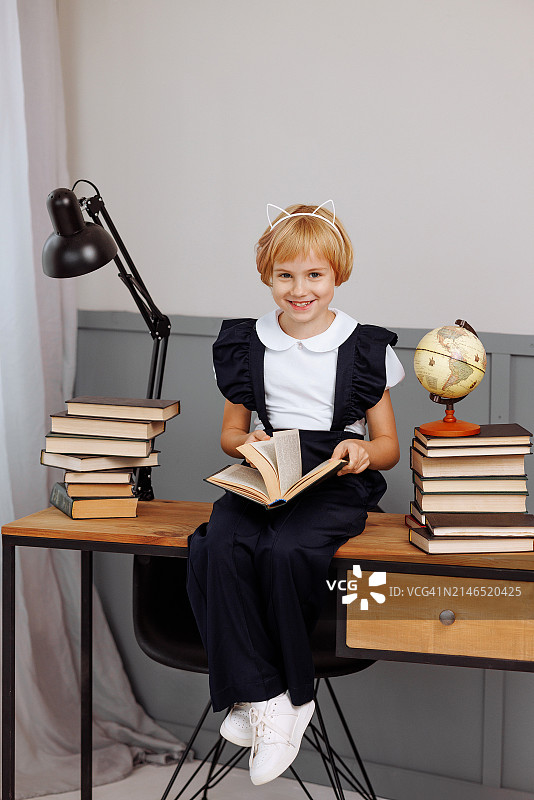 坐在阁楼风格的桌子旁读书的女学生。桌子上堆满了教科书图片素材
