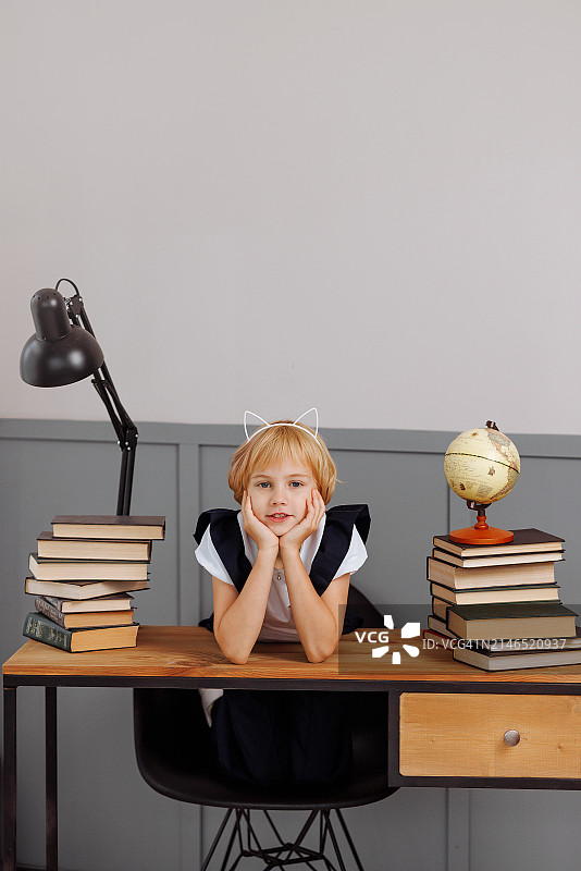 在阁楼风格的桌子上，双手托着头的女学生，桌子上堆着课本图片素材