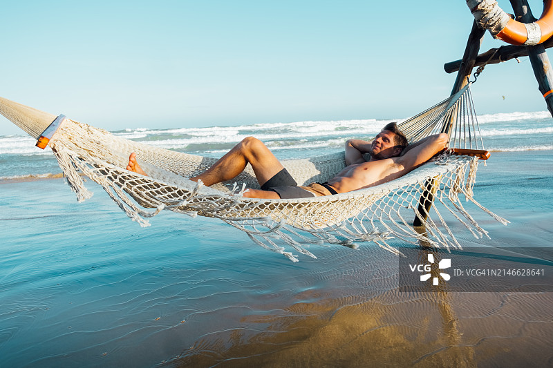 男子在海边吊床上放松身心图片素材