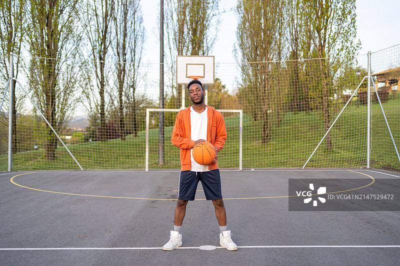站在户外篮球场上的年轻非裔美国男子图片素材