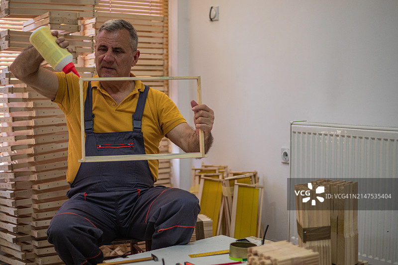 老人为蜜蜂准备带有蜂窝的木框图片素材