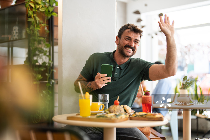 在咖啡店呼唤服务员的微笑男人图片素材