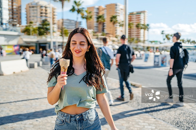在西班牙马拉加码头吃冰淇淋的年轻女人图片素材