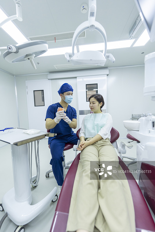 正畸医生用塑料牙齿向患者解释种植体图片素材