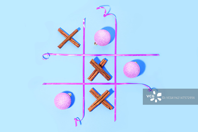 在淡蓝色背景上用肉桂棒和圣诞球玩井字棋游戏图片素材