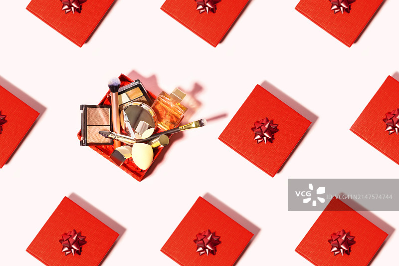 由红色礼品盒和带有女性美容化妆节日化妆套件的红色礼品盒制成的粉白色背景图案。图片素材