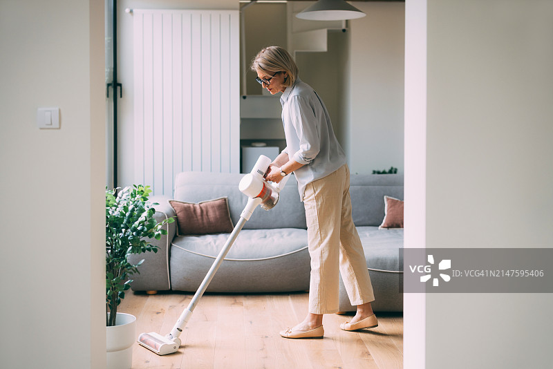 用无线吸尘器清洁房屋的女人图片素材