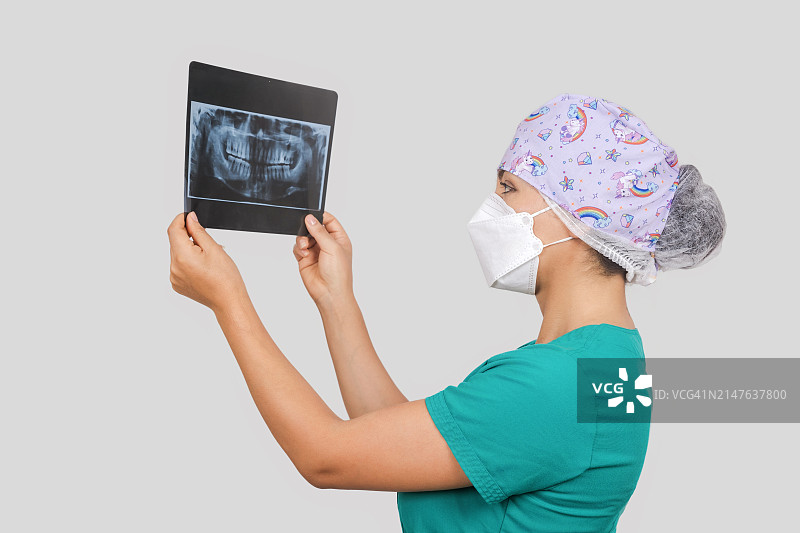 戴着口罩的女医生分析牙科X光片的肖像图片素材