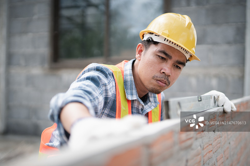 建筑工地：男性建筑工人检查墙体立面图片素材