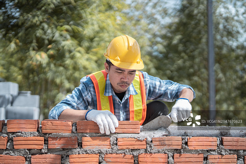 瓦工在建筑工地安装砖块，建筑外墙图片素材