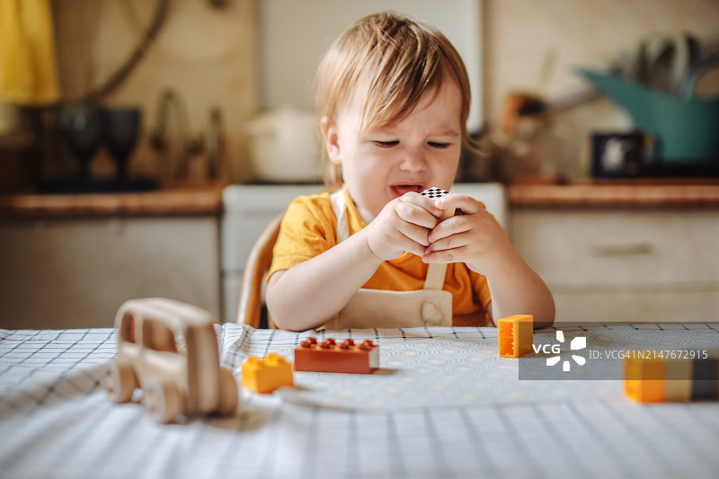 专心玩塑料积木的沮丧的幼儿图片素材