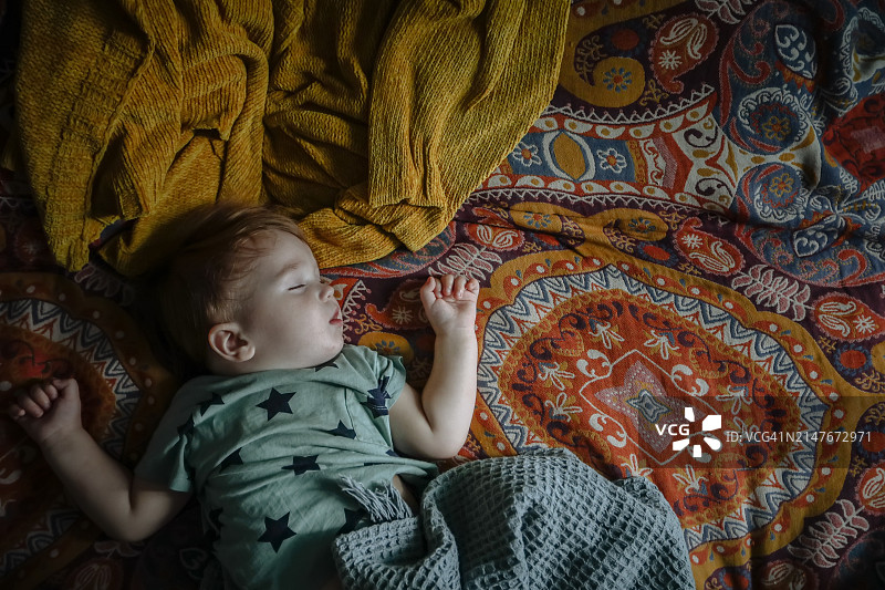 安静的睡眠：可爱的幼儿在东方床罩上幸福地小憩图片素材