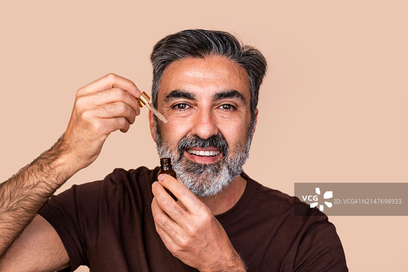 中年男人涂抹面部精油护肤图片素材