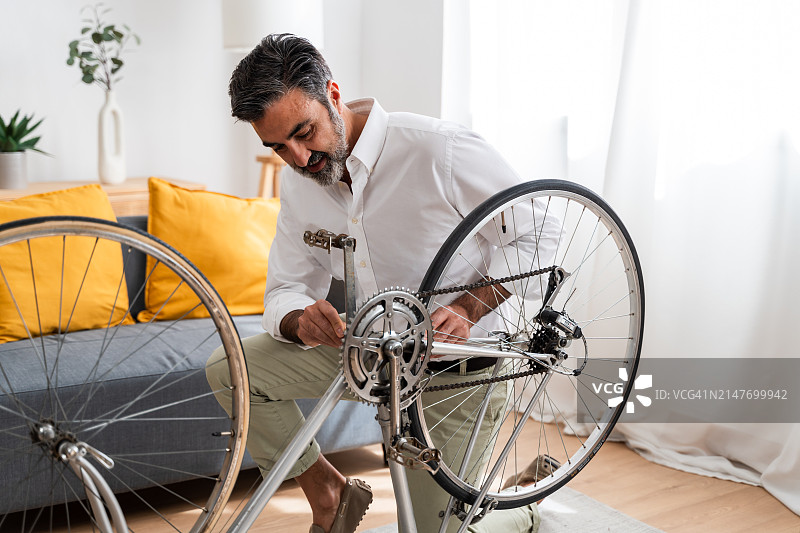 男人在家里修理自行车。图片素材