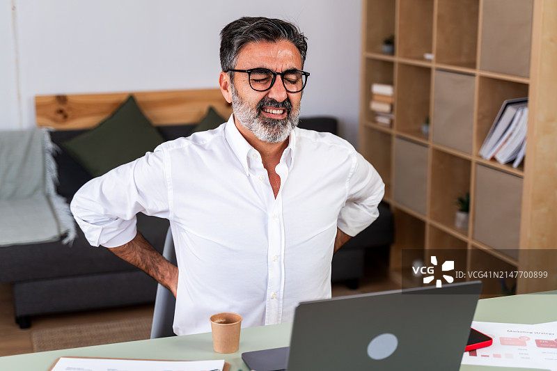 工作中感到背痛的商人图片素材