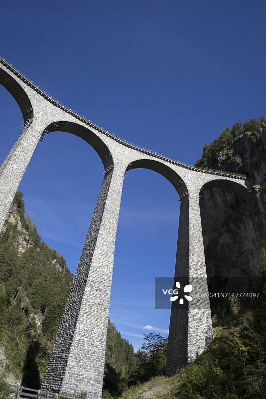 瑞士阿尔卑斯山石拱高架桥上的红色火车图片素材