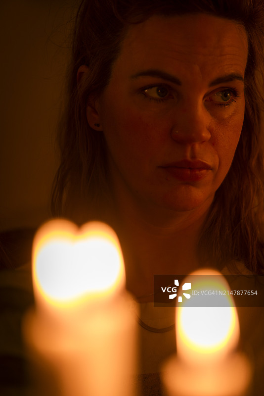 女子在燃烧的蜡烛后图片素材