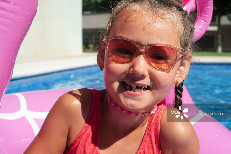 在游泳池里带着充气游泳圈的女孩。夏天。休息。假日。一个孩子学习游泳。小女孩的肖像。孩子们的消遣。健康和运动的生活方式。图片素材