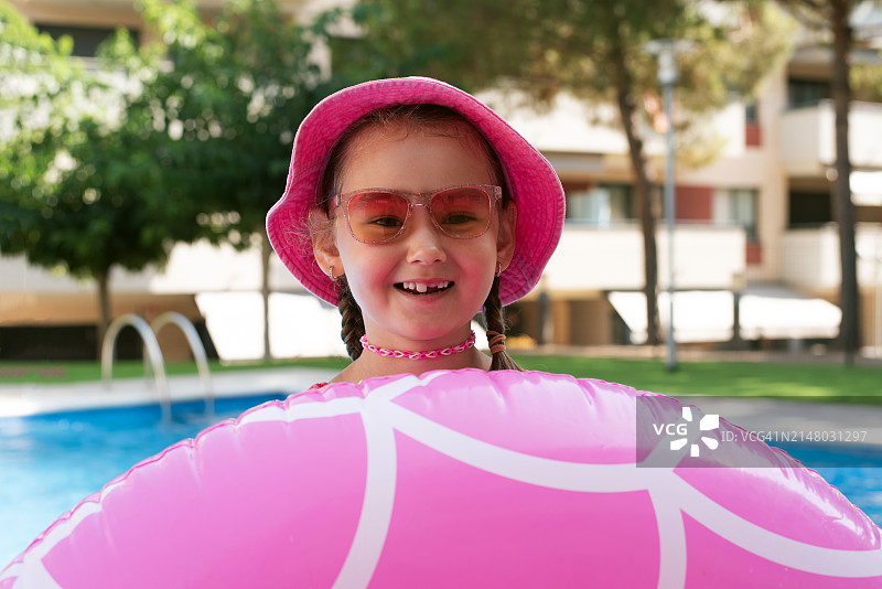 在游泳池里带着充气游泳圈的女孩。夏天。休息。假日。一个孩子学习游泳。小女孩的肖像。孩子们的消遣。健康和运动的生活方式。图片素材