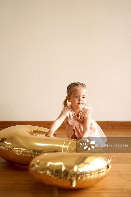 小女孩蹲在房间里触摸充气数字2图片素材