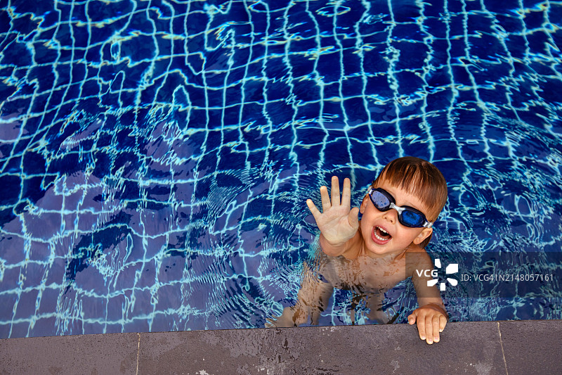 游泳池中微笑男孩的高角度肖像照图片素材