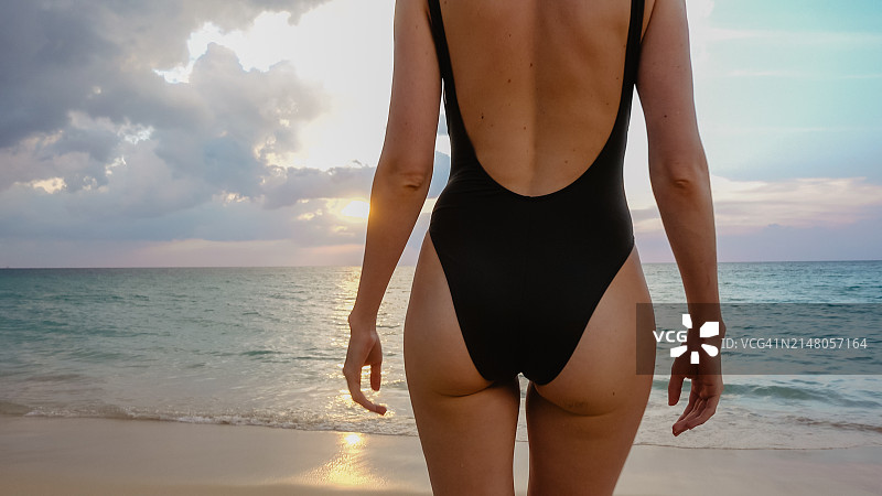 日落时女子站在海滩的腰部特写图片素材