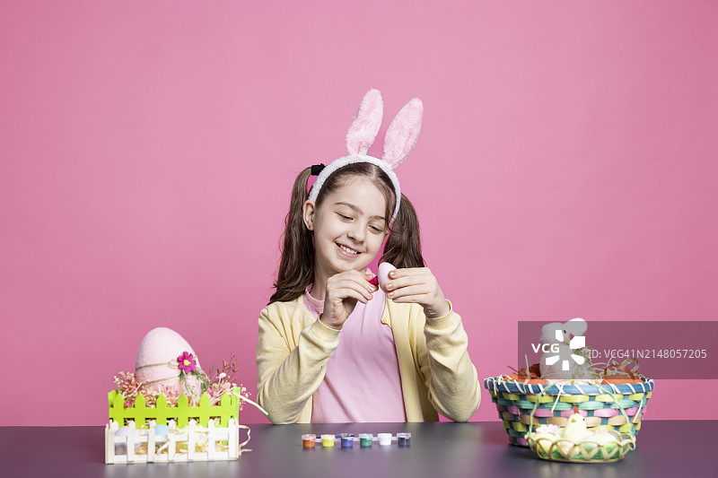 手拿复活节彩蛋，靠墙而坐的微笑女人像图片素材
