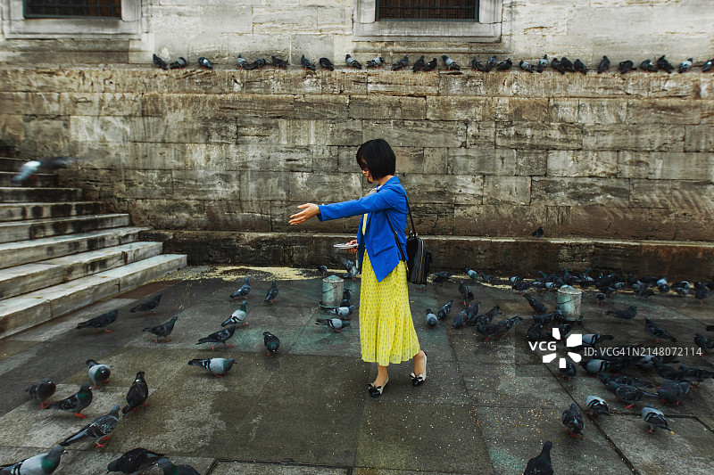 中国女人在伊斯坦布尔老城区喂鸽子图片素材