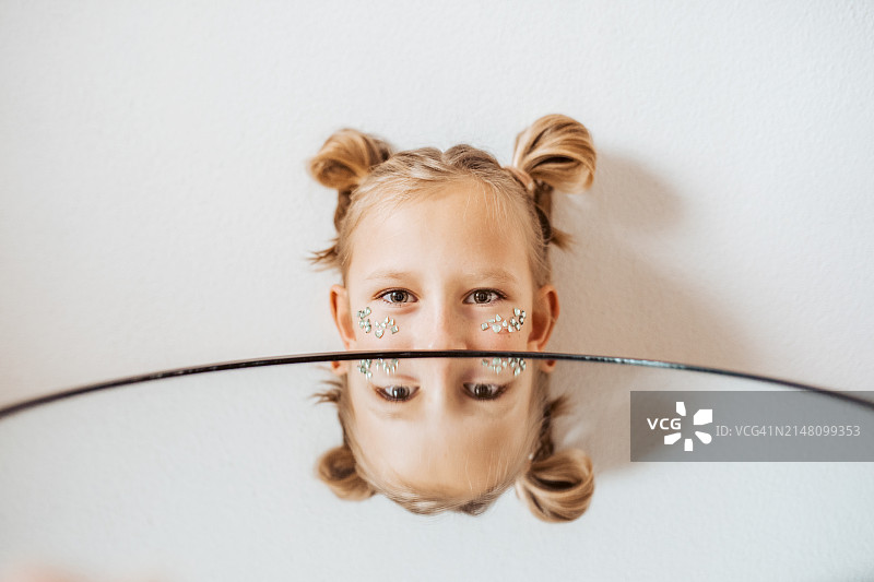 面部贴宝石的少女肖像，脸颊上饰有珠宝，镜中反射出部分面容图片素材