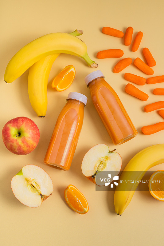 黄色背景上的两瓶鲜榨果汁，健康饮食理念图片素材