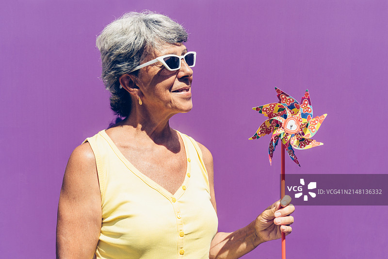 戴时尚太阳镜的快乐银发老妇用儿童风车庆祝生日图片素材