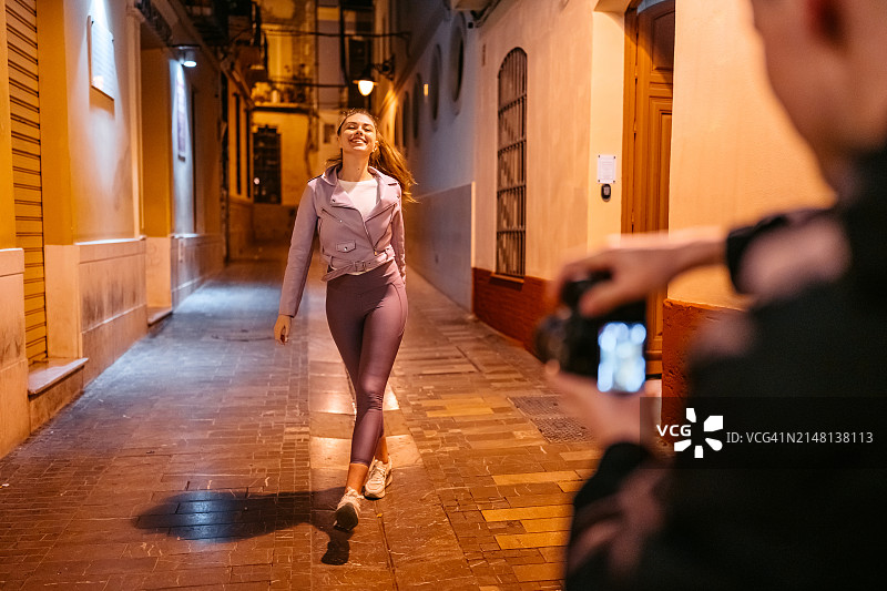 在西班牙马拉加的夜晚，男友用相机为街上的女友拍照图片素材