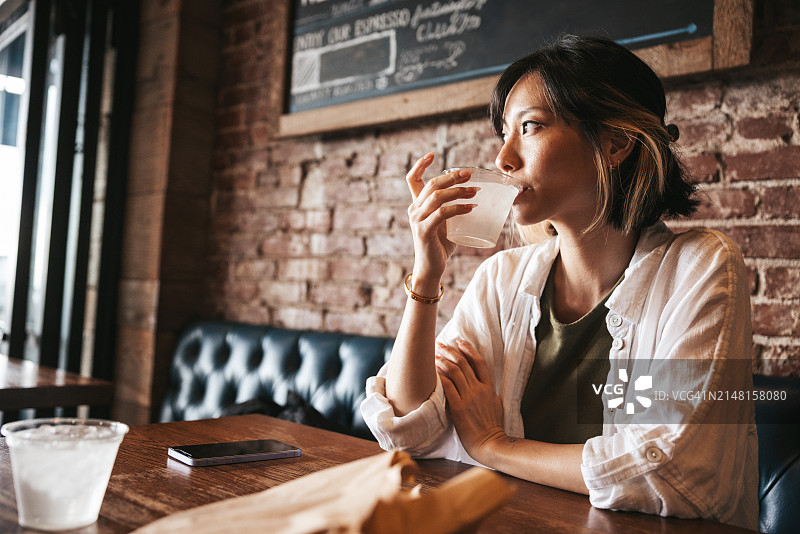 沉思的女人坐在餐厅里，望着窗外图片素材