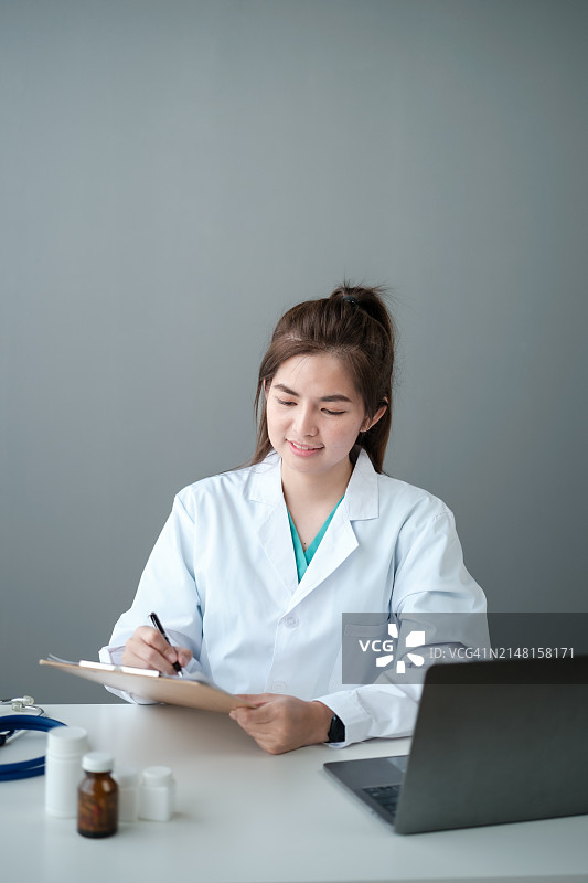 女医生在办公室办公桌旁使用笔记本电脑图片素材