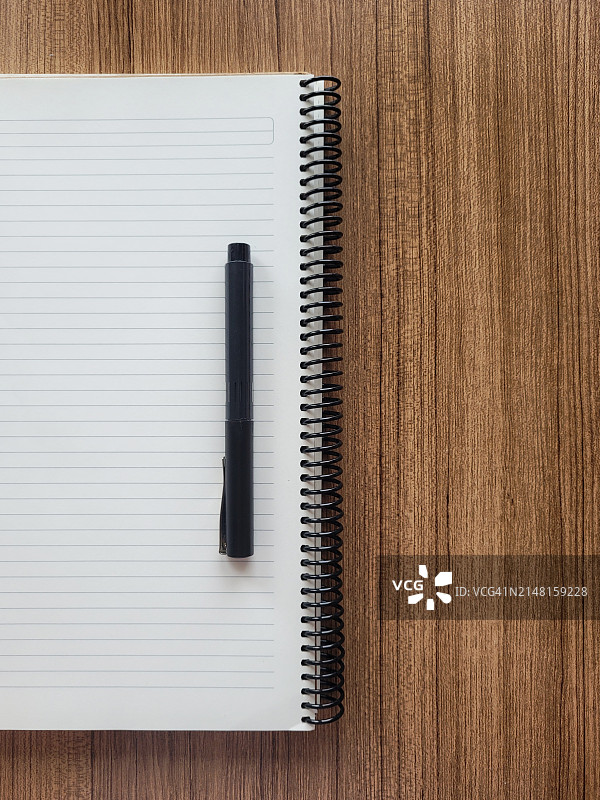 木桌上带钢笔的螺旋笔记本俯视图图片素材