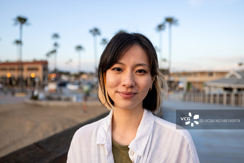 年轻女子在美丽的日落光线下看着镜头的人物肖像图片素材