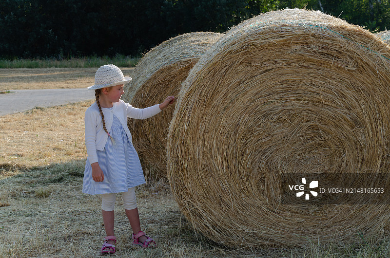 女孩站在田野的干草堆旁图片素材