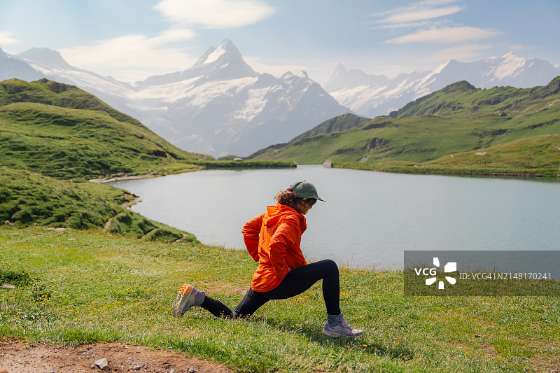 在瑞士阿尔卑斯山徒步旅行时伸展腿筋的女人图片素材