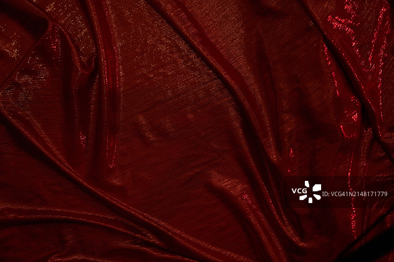 闪亮的红色面料和红灯。纺织时装生产、节日、迪斯科舞厅与优雅的礼服概念。带有复制空间的绿色艺术背景图片素材