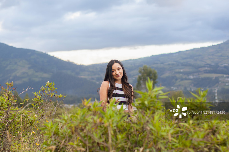 一名女子站在草地上，背景是晴空下的巍峨群山图片素材
