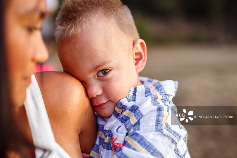 在海滩上和母亲在一起的害羞男孩看着镜头图片素材