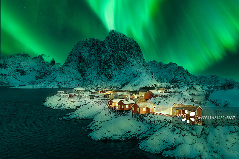 挪威罗弗敦群岛哈姆诺伊渔村和Festhelltinden雪峰背景下的北极光图片素材
