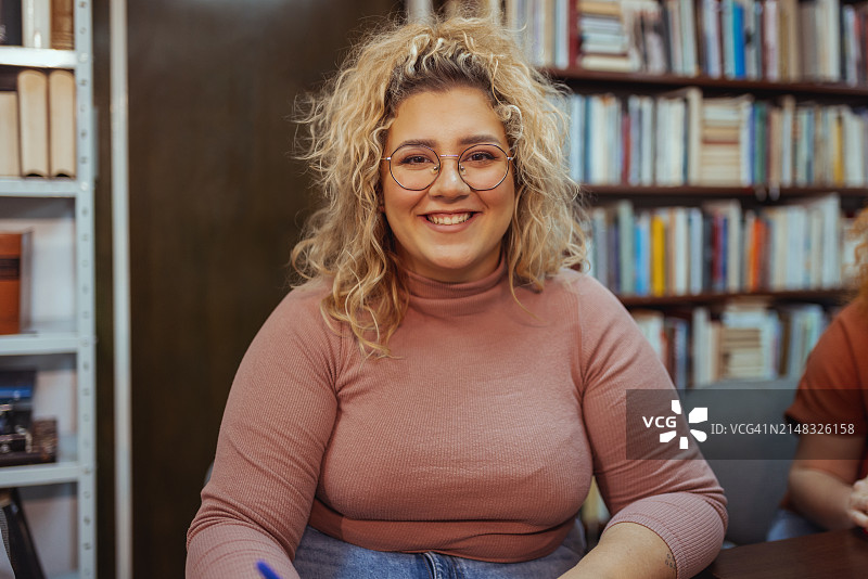 书店里看着镜头的年轻胖乎乎的女学生图片素材
