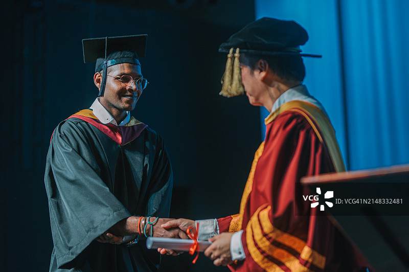 印度裔亚洲大学生在毕业典礼上与院长握手，获得文凭图片素材